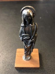 Imagen religiosa en metal sobre pie de madera